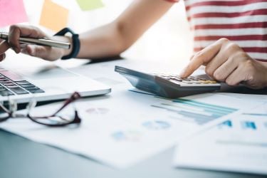 Image of individual using calculator sitting at a desk